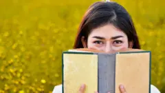 Una joven huele un libro.