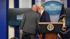 US President Donald Trump talks with a secret service agent before leaving a coronavirus briefing at the White House, August 10, 2020