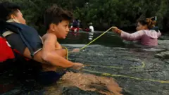 Una familia se sujeta a una soga para cruzar el río