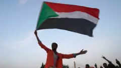 Sudanese protestors celebrate in the streets of Khartoum after ruling generals and protest leaders announced they had reached an agreement on the disputed issue of a new governing body on 5 July