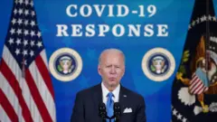 Biden con un letrero en el fondo: respuesta al covid-19