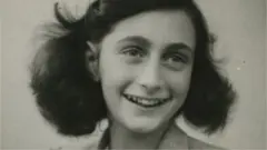 Anne Frank smiles in a black and white photo
