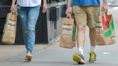 Personas cargan bolsas de papel