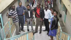 Bwana Munene (hagati, wambaye uupira w'umutuku) ari kumwe na bamwe mu bakodesha inzu ze