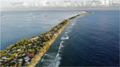 An aerial view of a strip of land between the Pacific Ocean and lagoon in Funafuti, Tuvalu.