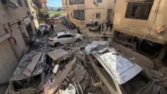 عمال إنقاذ وسكان محليون يتفقدون الأضرار التي لحقت بمبنى إثر غارة إسرائيلية على منطقة الشويفات
