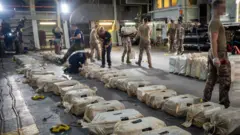 Security operatives inspecting sacks suspected to contain cocain seized from a fishing boat off the gulf of guinea