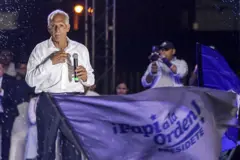 Nasry Asfura en un escenario durante la campaña electoral. Frente a él se ve una bandera en la que dice: "¡Papi a la orden! Presidente".