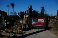 پرچم آمریکا که بر دروازه حیاط خانه‌ای که کاملا سوخته آویزان شده ادست