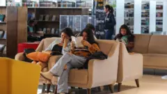 Pessoas sentadas em um sofá lendo