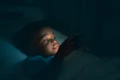 Garçon utilisant un téléphone dans la pénombre