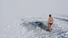 Mulher toma banho de gelo em um lago congelado