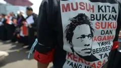 Seorang pengunjuk rasa Indonesia mengenakan kaos bertuliskan, "Musuh kita bukanlah keberagaman agama atau ras, melainkan pemerintah yang menindas" dalam protes terhadap kegagalan pemerintah Indonesia dalam menjamin kebebasan beragama di Jakarta pada tanggal 8 April 2013.