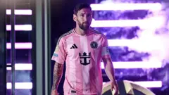Lionel Messi entrando em campo. Ele usa a camisa rosa do Inter Miami