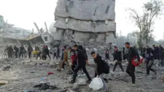 イスラエルとハマスの停戦合意発効を受け、がれきの合間をぬって家へ戻ろうとするパレスチナの人たち（19日、ガザ地区北部）