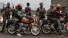 Des motos-taxis conduisent des miliciens Wazalendo (Patriotes en swahili), qui font partie d'un groupe de milices pro-gouvernementales, le long de la route menant à l'entrée de la ville de Sake, à 25 km au nord-ouest de Goma, le 23 janvier 2025. 