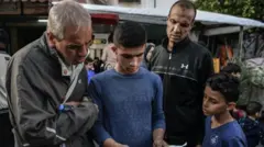رجلان وصبيان في أحد شوارع غزة يقرأون منشوراً يحتوي على تحذير للجيش الإسرائيلي من أجل الإخلاء