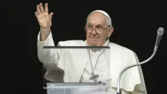 Papa Francisco usando vestes brancas e acenando
