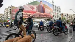 Motorists pass under a banner featuring a portrait of Mojtaba Khamenei, Iran's new Supreme Leader, on a busy street in Tehran