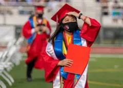 Jovem de máscara em cerimônia de formatura ao ar livre
