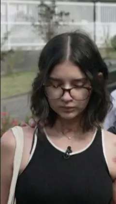 කණ්නාඩි දෙකක් පැළඳ, කොණ්ඩය කොටට කැපූ තරුණියක් බිම බලාගෙන ඉන්නවා.