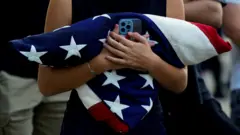 bandeira americana dobrada entre os braços de uma mulher.