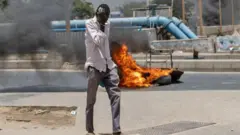 Umugabo yihanagura mu maso ubwo yari anyuze iruhande rw’imipine irimo gushya hafi ya Kaminuza Cheikh Anta Diop, i Dakar mu murwa mukuru wa Sénégal, ku itariki ya mbere Kamena (6) mu 2023