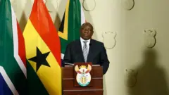 Ramaphosa looking at di camera wit Ghana and South Africa flag for di back