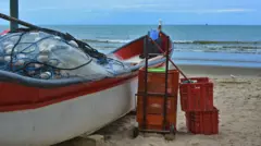 Barco na areia com rede de pesca e alguns caixotes para peixes