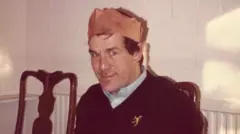 Photograph of Ronnie Lockwood wearing a Christmas cracker hat.