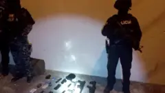 Dois policiais ao lado de armas no chão