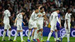 بازیکنان رئال مادرید با پیراهن های سفید در زمین بازی که پس از زدن یک گل خوشحالی می‌کنند.