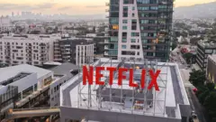 O telhado dos escritórios da Netflix em Los Angeles, com um grande letreiro vermelho NETFLIX em primeiro plano e a paisagem urbana ao fundo