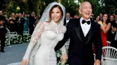 Lauren Sánchez wears a Dolce & Gabbana haute couture gown while Jeff Bezos places his arm around her while wearing a smart black tuxedo