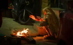 दिल्ली में आग तापती एक महिला