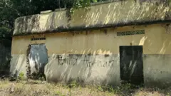 Casa em ruínas com a inscrição “Família Arenas” em uma de suas paredes.