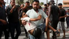Haleellaa haaraa Israa'el giddugala Gaazaa Dir Al-Balaa keessatti raawwatte hordofee nama daa'ima baatee gara hospitaalaa geessu
