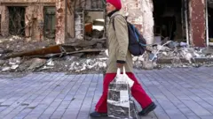 Une femme passe devant des bâtiments détruits à Marioupol.