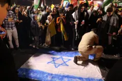 Em foto noturna, homem aparece ajoelhadobilhetes prontos para hojebandeirabilhetes prontos para hojeIsrael, observado por várias pessoas