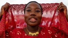 A Ivory Coast wata Musulma ta sanya jan kaya tana gyara hijabinta, gashin kanta a rufe ya yin shagulgulan Sallah