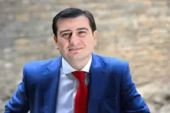 Азер Гасымлы в синем костюме и ярко-красном галстуке.