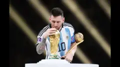مسی هنگام بوسه بر جام جهانی در قطر