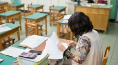 一名國小教師正在改作業的示意照片。