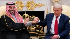 ホワイトハウスで互いに手を取り合うトランプ氏とムハンマド皇太子