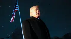 星空と星条旗を背に黒いコートを着たトランプ米大統領