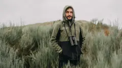 Homem com binóculos em paisagem rural