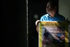 Reynaldo Santos Vanegas muestra un cartel con fotos de su hijo Jonathan Santos Castillo, arrestado durante el estado de emergencia decretado por el gobierno salvadoreño para combatir a un grupo criminal, durante una entrevista en Soyapango, el 25 de octubre de 2024.