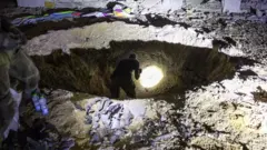 दक्षिण इस्रायलमध्ये इराणच्या क्षेपणास्त्र हल्ल्यानंतर पडलेल्या विवरात तपासणी करणारा पोलीस अधिकारी