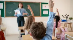 Students raising their hands in a classroom.