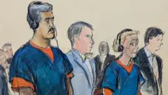 オレンジ色の囚人服と紺色の半袖シャツを着た白髪まじりの男性とブロンドの女性の法廷画。男女の間には弁護士が立っている